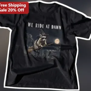 We Ride at Dawn Raccoon Witch Halloween Graphic Tee Funny Meme Shirt Gift available at our Los Angeles warehouse